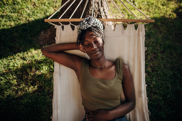 Black woman relaxing in a hammock outdoors in back yard in preconception mode