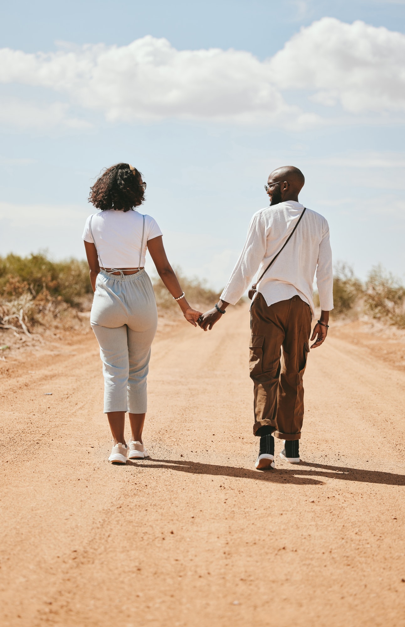 Black couple, love and holding hands back view in nature walking on vacation on desert, sand or dir